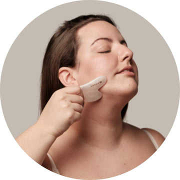 Chica masajeando su rostro con una gua sha, representando la rutina de cuidado facial con accesorios naturales para una piel luminosa y saludable