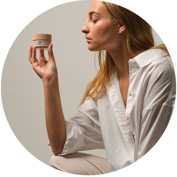 Chica observando una crema facial, representando el cuidado de la piel con fórmulas naturales y ecológicas para una belleza consciente