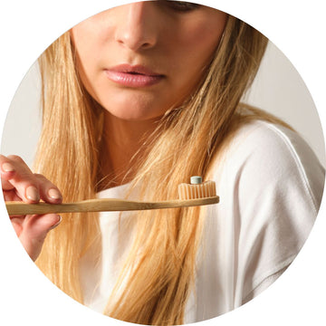 Chica con una pastilla de nuestra pasta de dientes sobre el cepillo de dientes justo antes de llevar a cabo su rutina de higiene bucal