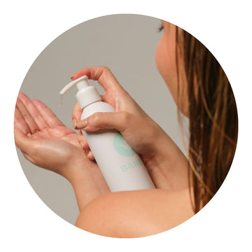 Chica aplicándose gel de peinado natural en la mano, preparándose para darle forma a su peinado de manera saludable y sostenible