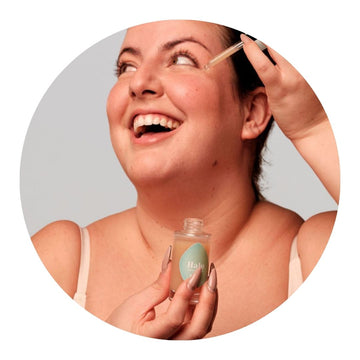 Chica aplicándose sérum facial, disfrutando de la hidratación y luminosidad que ofrece una rutina facial natural con ingredientes ecológicos.