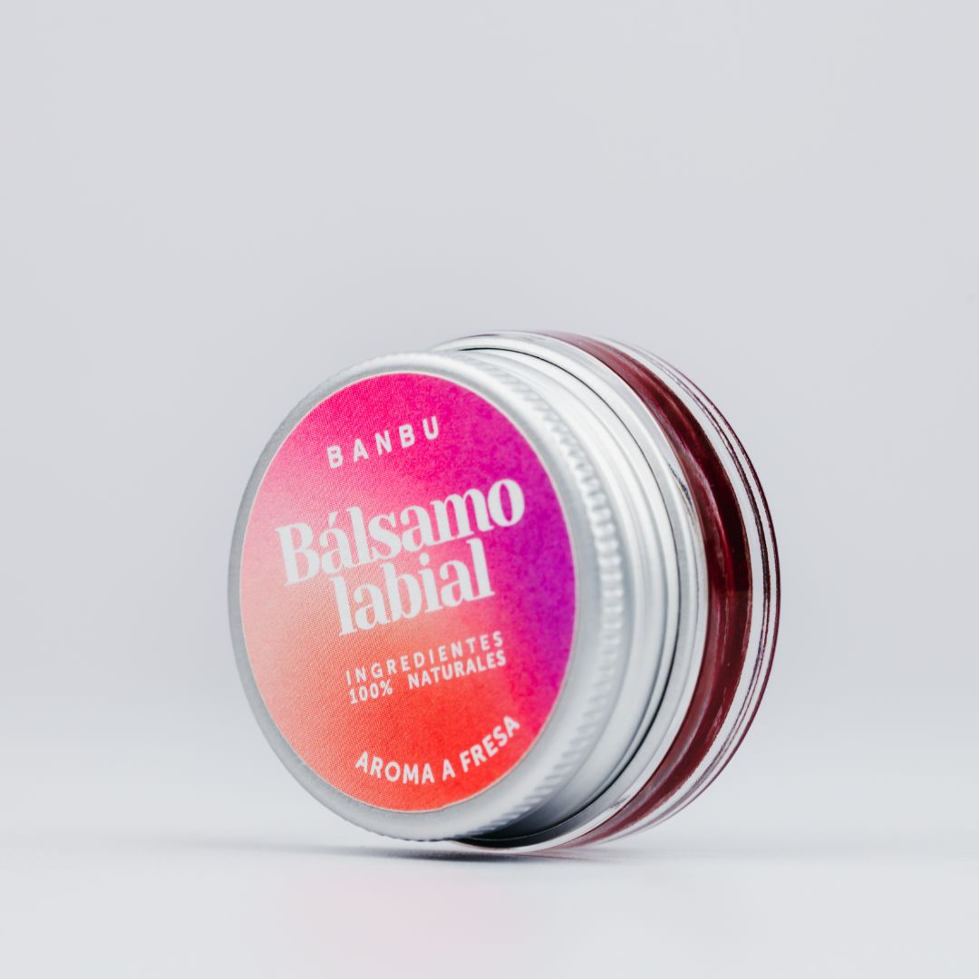 Bálsamo labial ecológico de Banbu con aroma a fresa y un sutil toque de color, en un envase de cristal con tapa de aluminio, destacando su formulación 100% natural y su diseño sostenible y libre de plásticos.