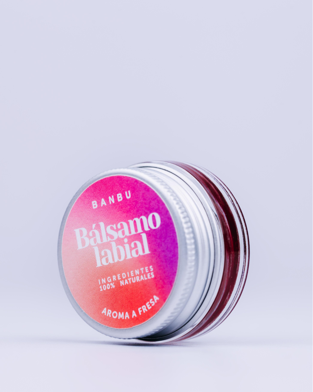 Bálsamo labial con color fresa en tarro de cristal.