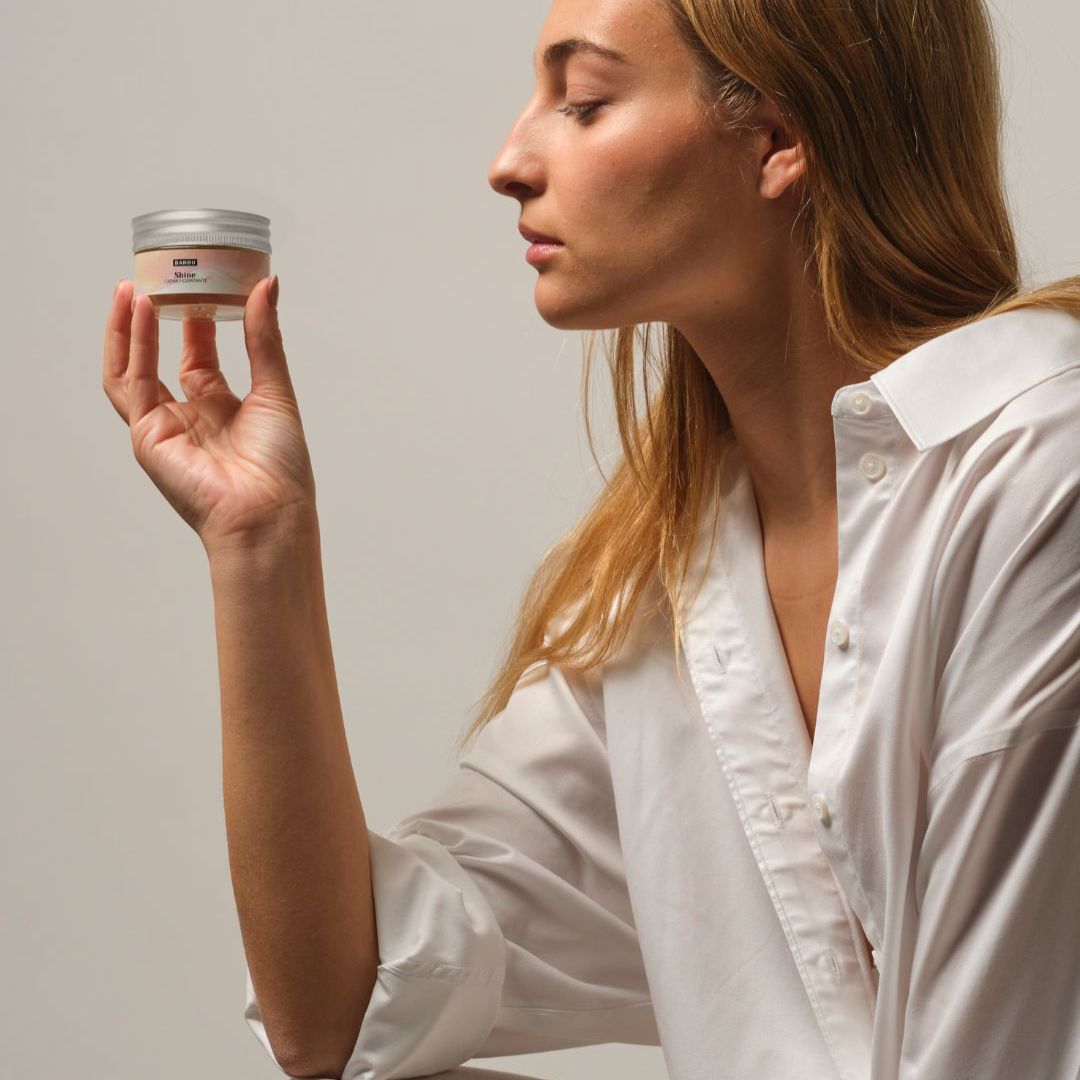 Mujer sosteniendo y observando la crema facial ecológica hidratante Shine de Banbu, reflejando una rutina de cuidado facial natural y consciente con ingredientes ecológicos.