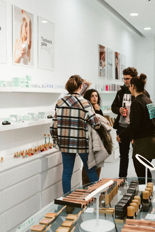 Interior de la tienda de banbu donosti en su inauguración, con algunas personas que nos acompañaron y se observan los expositores de productos a los laterales y una mesa de cristal con productos también. 