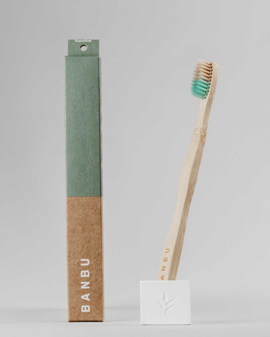 Cepillo de dientes de bambú con cerdas suaves verde junto a su packaging biodegradable