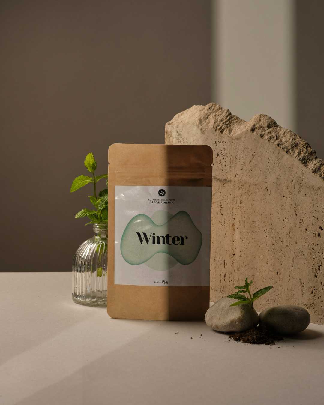 Bolsa kraft de la pasta de dientes de menta Winter de Banbu expuesta junto a hojas de menta fresca y piedras