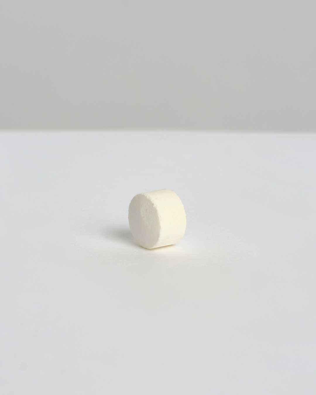Primer plano de una sola pastilla de dentífrico natural Autumn de Banbu, mostrando su textura sólida y compacta con un refrescante sabor canela, fórmula anticaries y vegana.